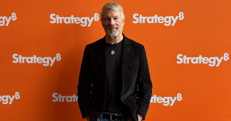 Michael Saylor standing in front of orange Strategy branded wall